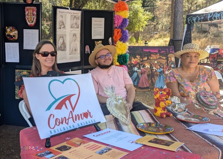 Three people sitting behind a display table